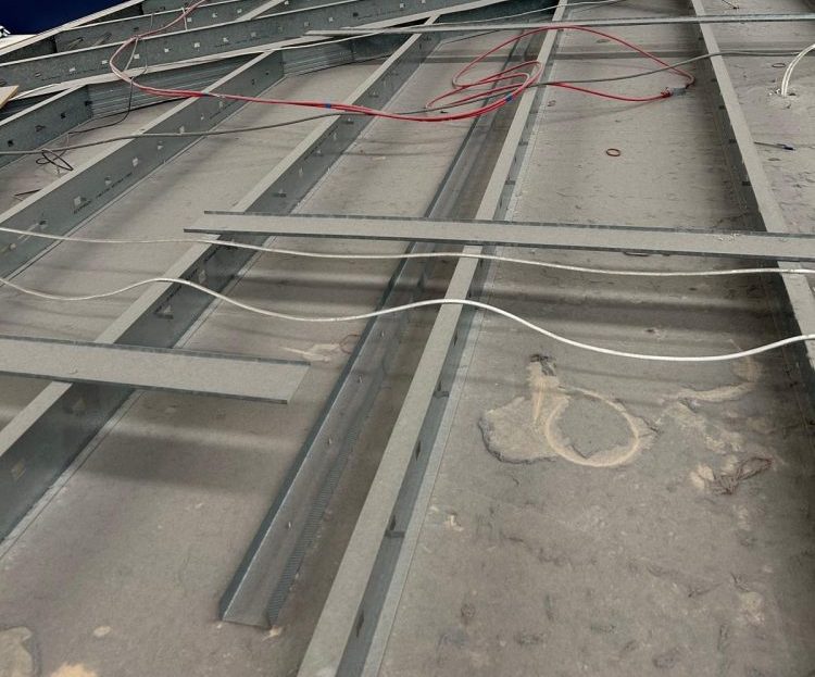 This image highlights the need for high access cleaning. The image shows the top of a suspended ceiling structure, possibly in a commercial or industrial building. The entire surface is heavily covered in dust, suggesting the area hasn’t been cleaned in a while. it is not only unhygienic it is a clear fire hazard.
