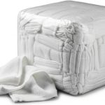 A large, tightly packed cube of white towelling rags with one towel partially pulled out and draped over the side. The towels are soft and absorbent making them perfect for use in the cleaning industry.