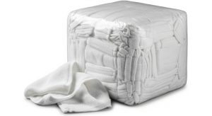 A large, tightly packed cube of white towelling rags with one towel partially pulled out and draped over the side. The towels are soft and absorbent making them perfect for use in the cleaning industry.